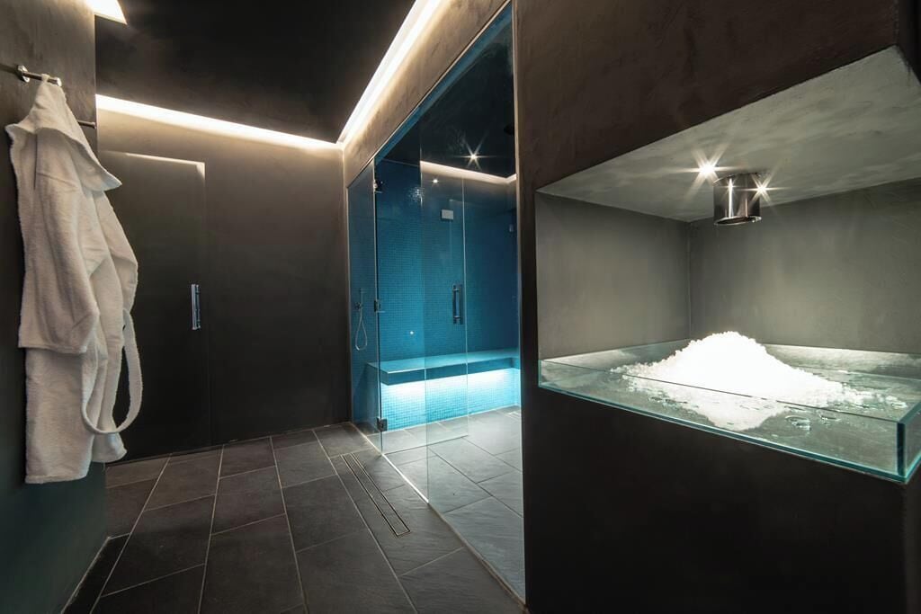Un baño moderno con cabina de ducha de vidrio, un lavamanos de vidrio y una sustancia blanca, y un perchero para toallas.