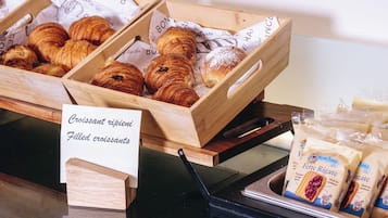 Mostra de croissants i croissants farcits en caixes de fusta, amb un cartell que indica els tipus de pastissos disponibles.