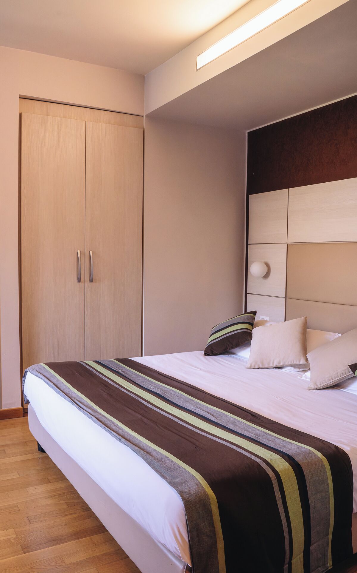 A bedroom with a bed, a wardrobe, and a headboard.