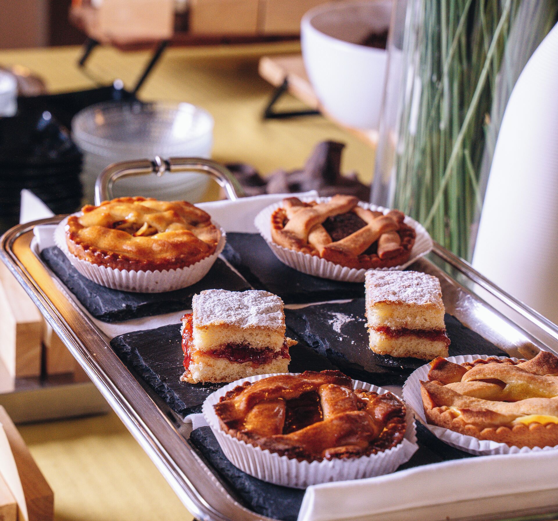 Un plateau rempli d’une variété de pâtisseries, notamment des tartes et des gâteaux, est présenté sur une table.