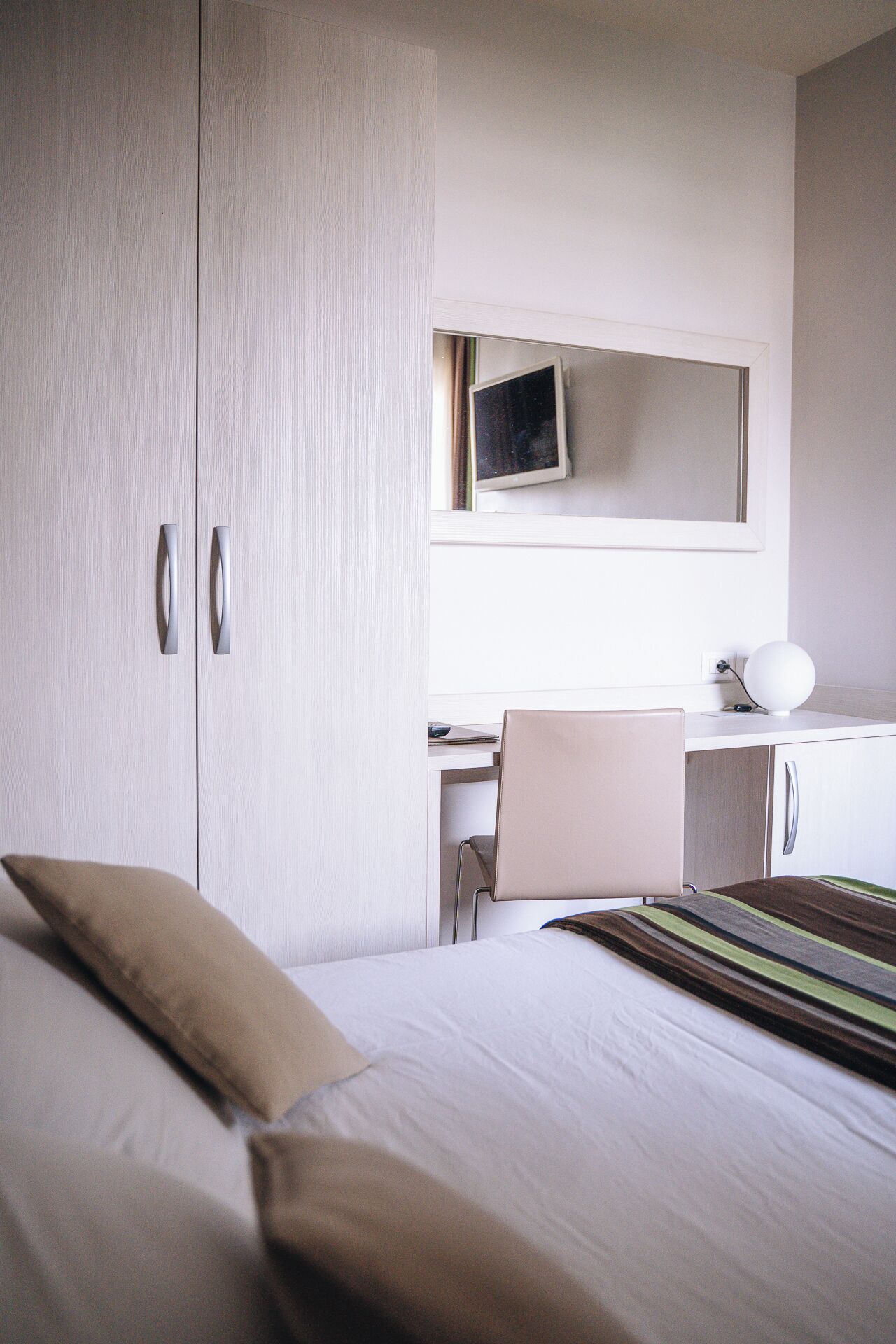 Hotellihuone, jossa on sänky, työpöytä, tuoli, televisio ja vaatekaappi.