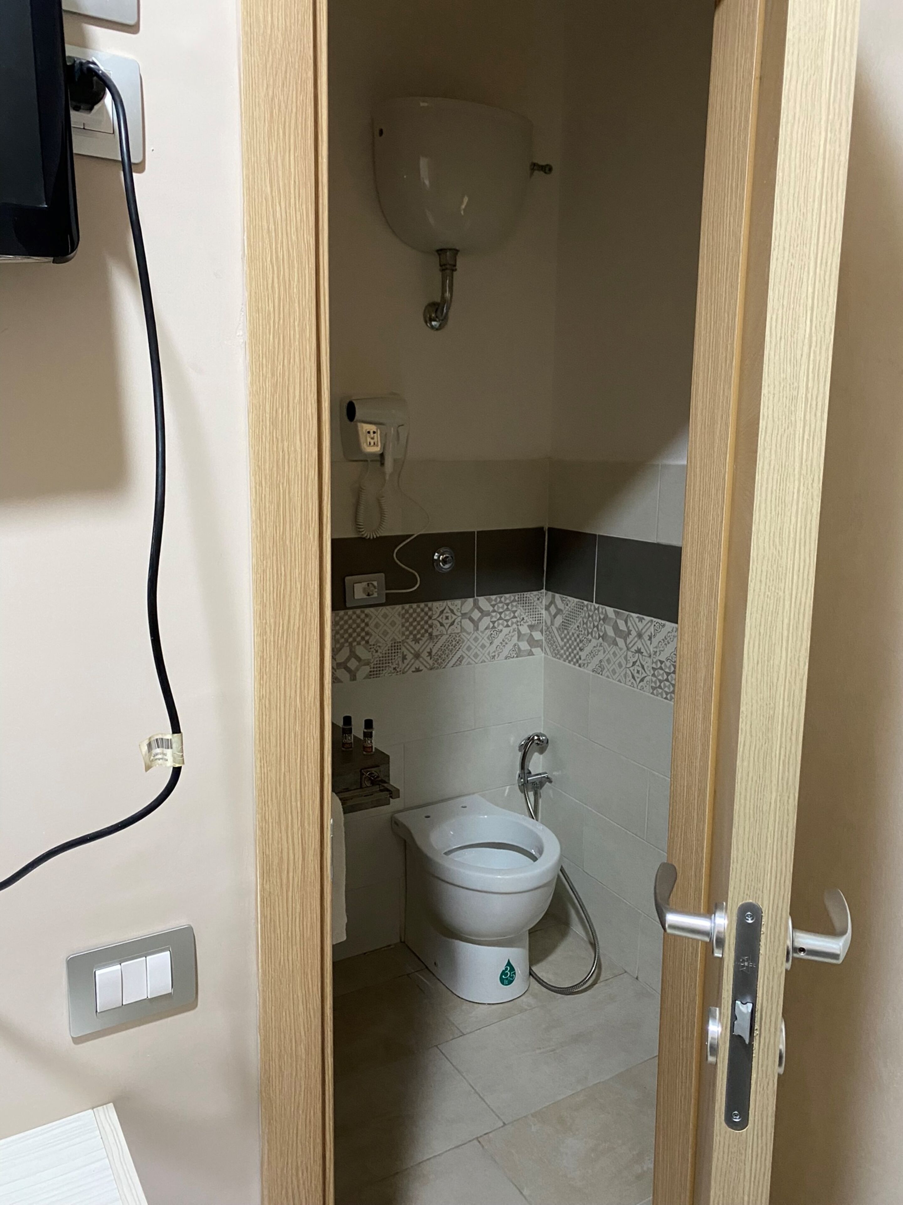 Un baño pequeño con inodoro, lavamanos y secador de pelo en la pared.