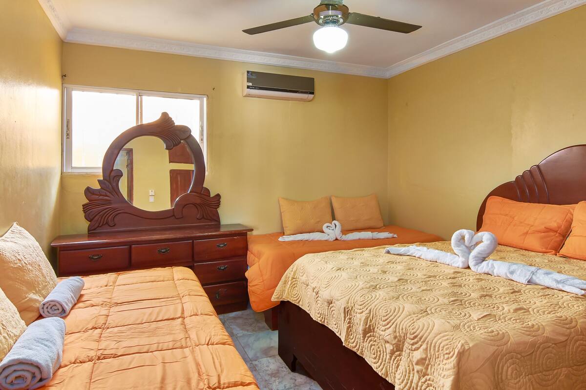 Ein Hotelzimmer mit zwei Betten, einem großen Spiegel und einem Deckenventilator.