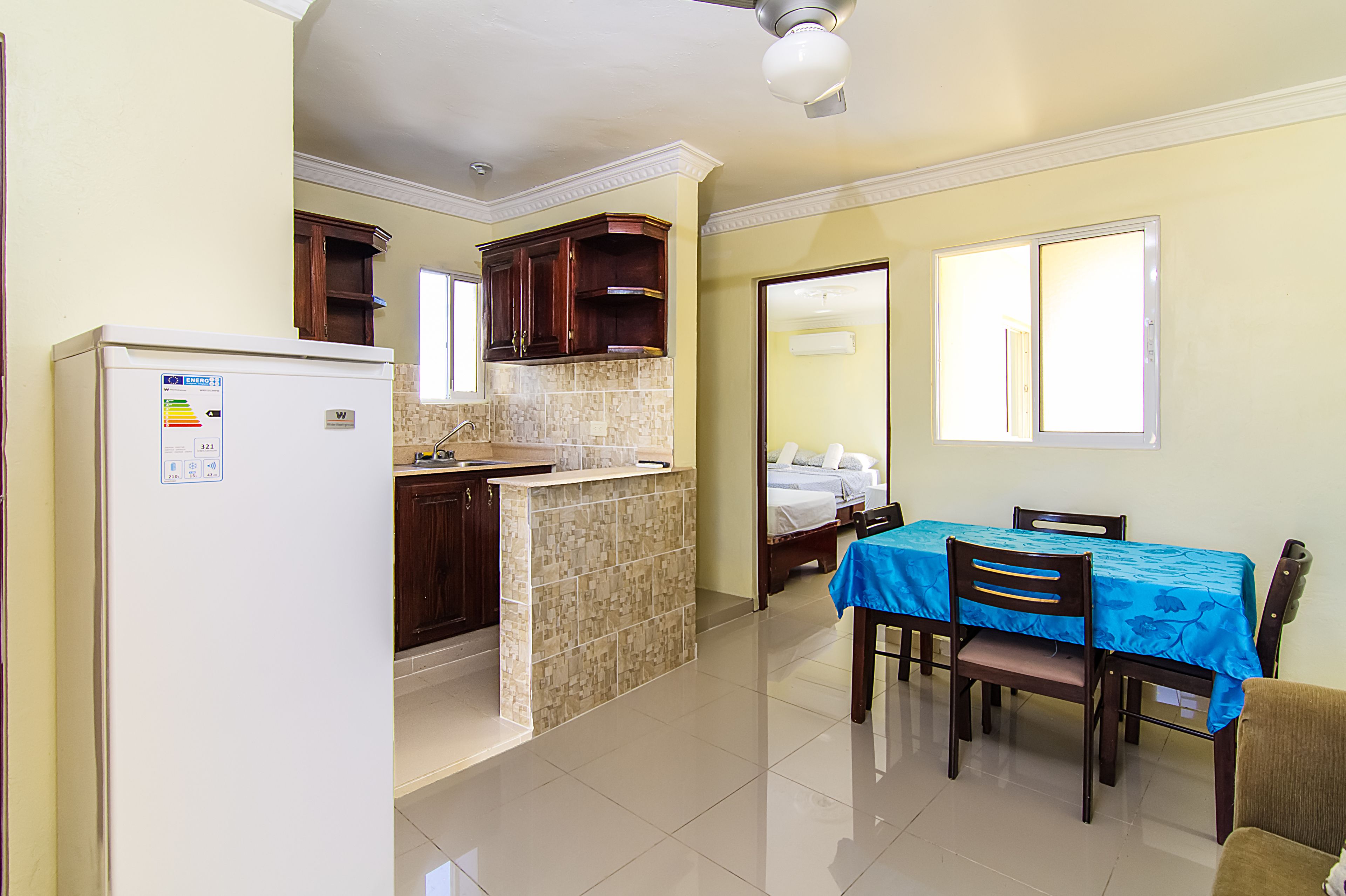 Una cocina compacta con refrigerador, pileta y comedor con mesa y sillas.