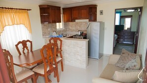 A compact kitchen with wooden cabinets, a central island, and a refrigerator. - Tropical Island Aparthotel (Santo Domingo Este)