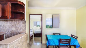 A compact hotel room with a kitchenette, a dining area with a blue tablecloth, and a view through the door. - Tropical Island Aparthotel (Santo Domingo Este)