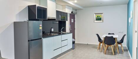 Una cocina moderna con refrigerador empotrado, estufa y comedor con mesa y sillas.