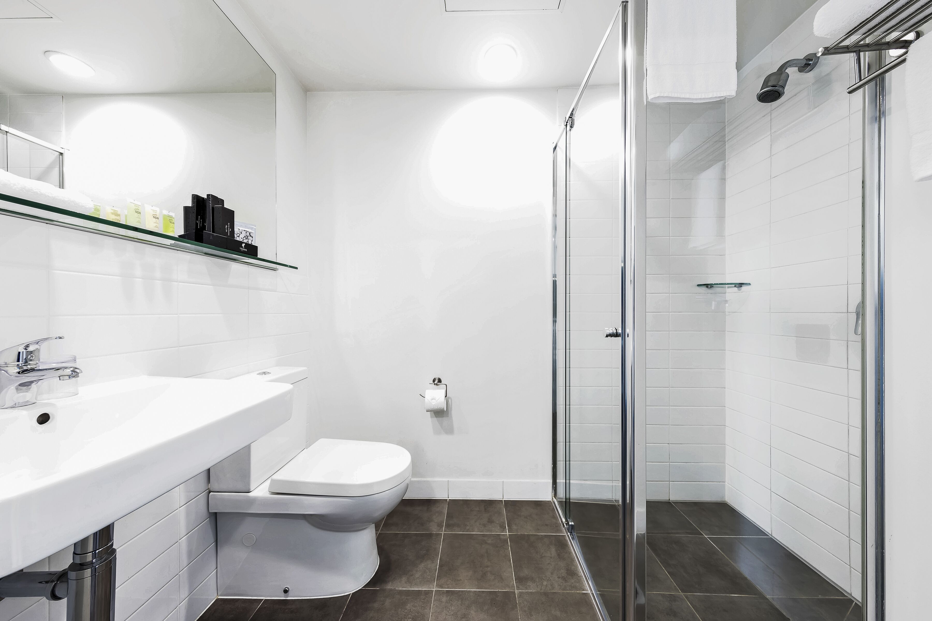 A modern bathroom with a white sink, toilet, and glass shower enclosure.
