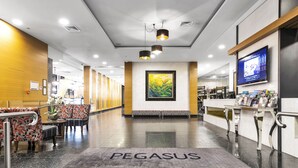 A modern hotel lobby with a reception desk, seating area, and a large painting on the wall. - Pegasus Apart'Hotel (Melbourne)
