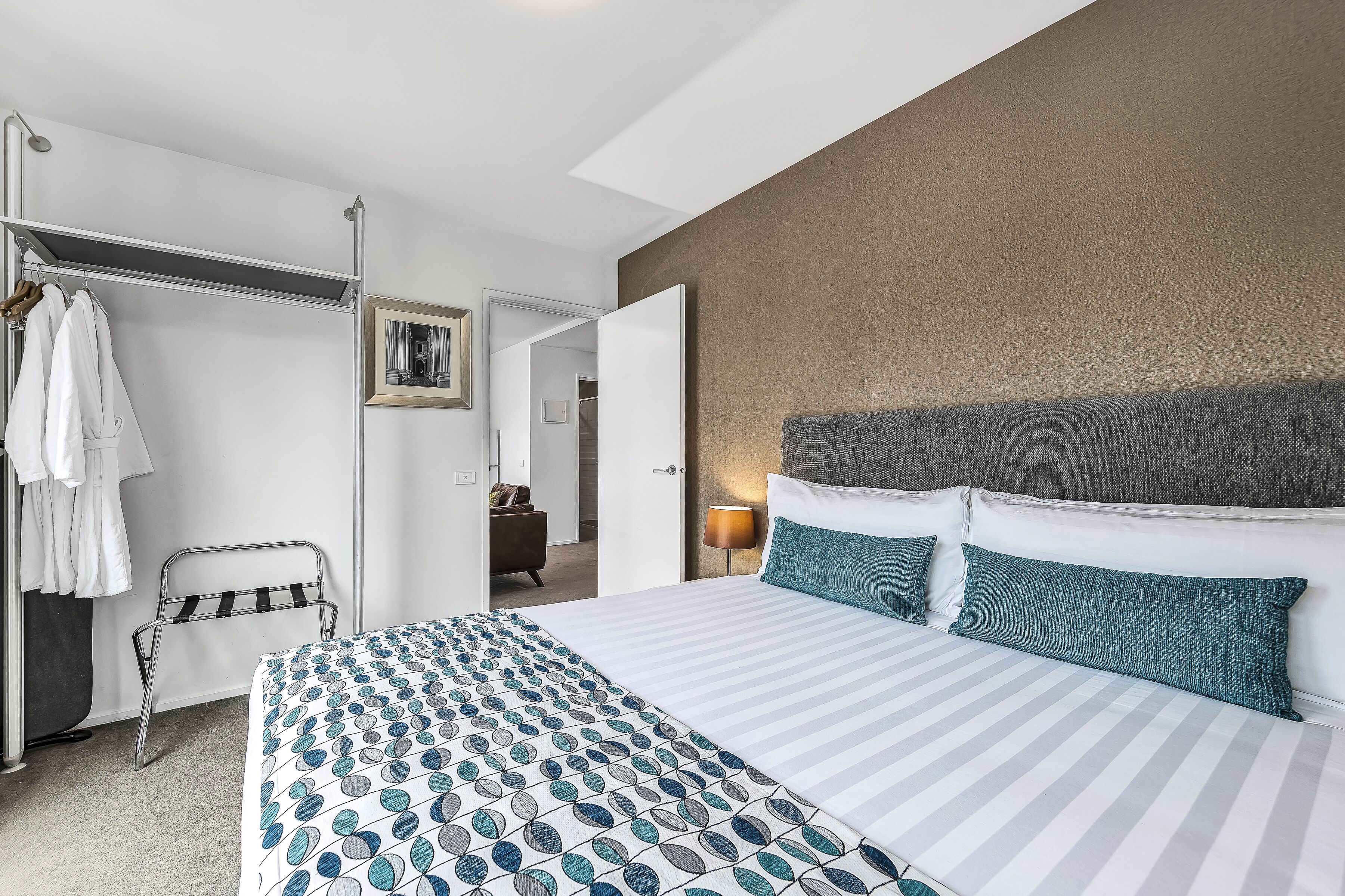 Habitació d'hotel moderna amb un llit gran, un armari i un bany visible a través d'una porta oberta.