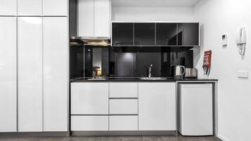 A modern kitchen with white cabinetry, a built-in stove, and a small refrigerator.
