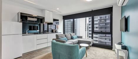 A modern apartment with a kitchen, a sofa, a small round table, and a TV.