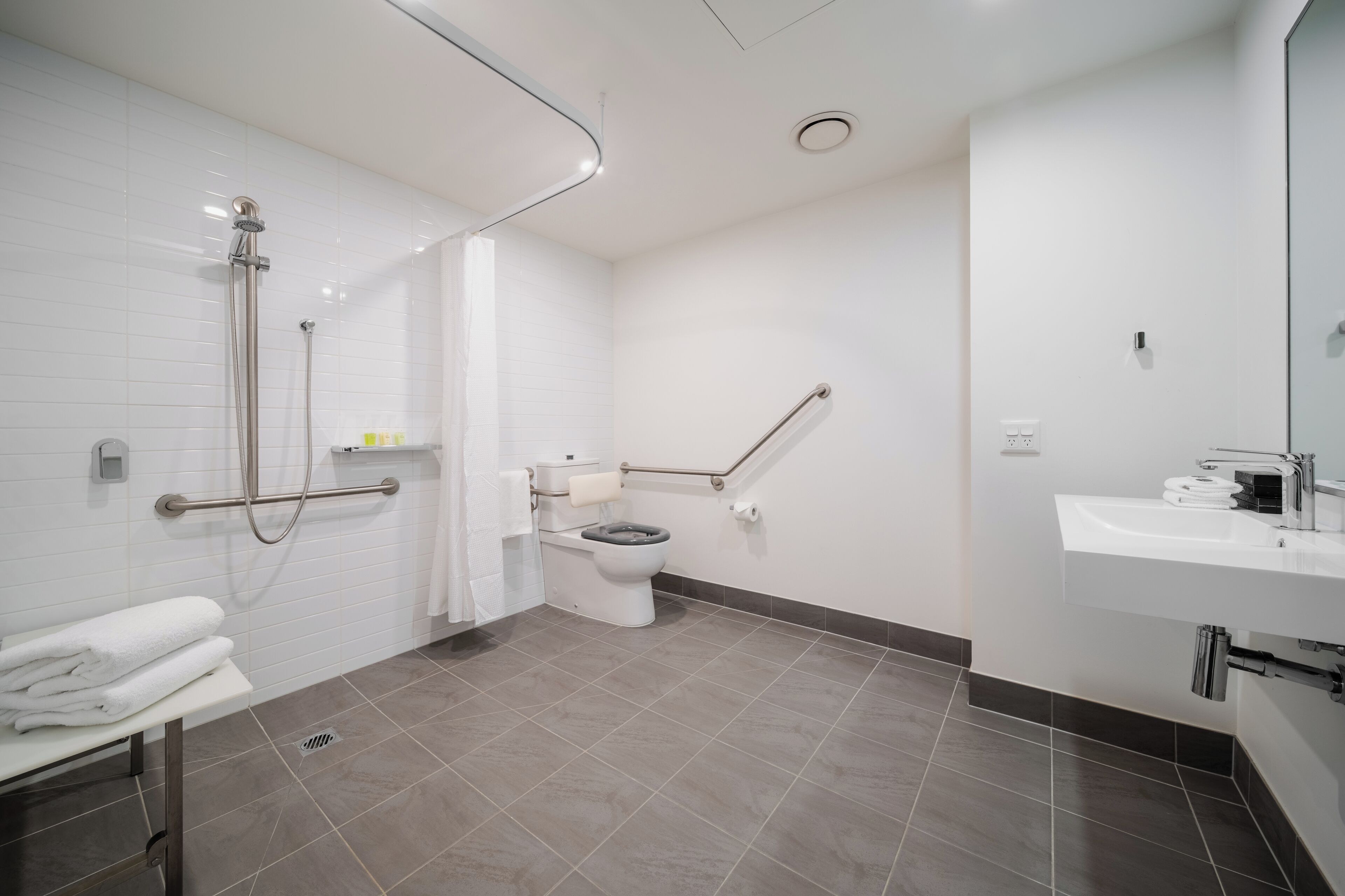 A modern bathroom with a shower, toilet, and sink.