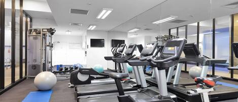 Une salle de sport équipée de tapis de course, de ballons d’exercice et d’appareils de musculation.