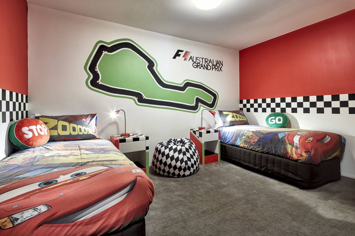 A bedroom with two beds, a racing-themed wall mural, and a checkered pattern on the walls.