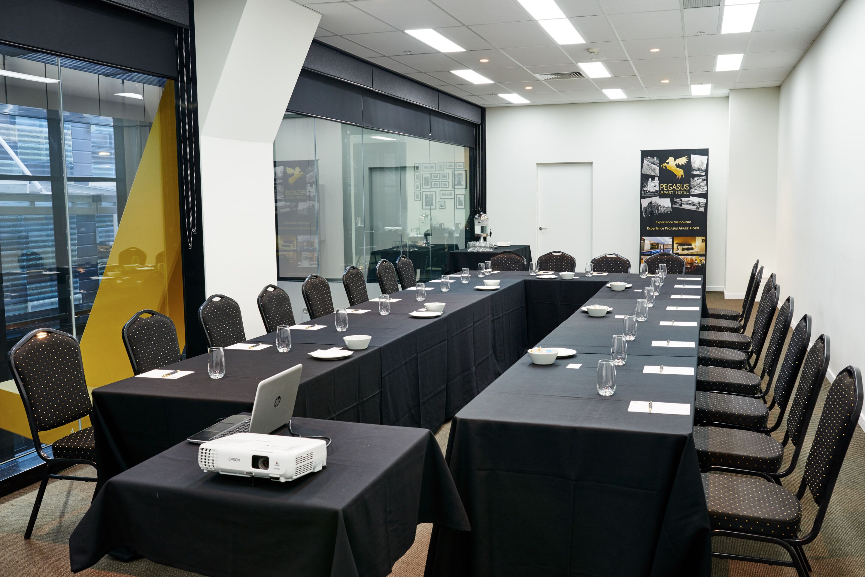 Une salle de conférence équipée d’une longue table, de chaises, d’un projecteur et d’un ordinateur portable.