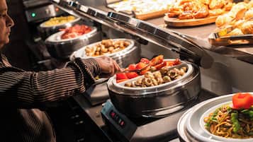 Een buffet met diverse gerechten, waaronder een schotel met champignons en groenten.