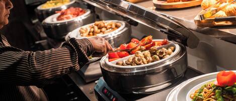 A buffet with various food options, including a dish with mushrooms and vegetables.