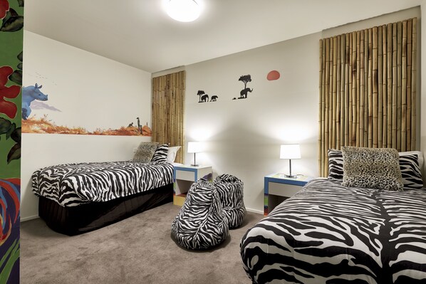 Un dormitorio con dos camas, sillones de mimbre y un mural en la pared.