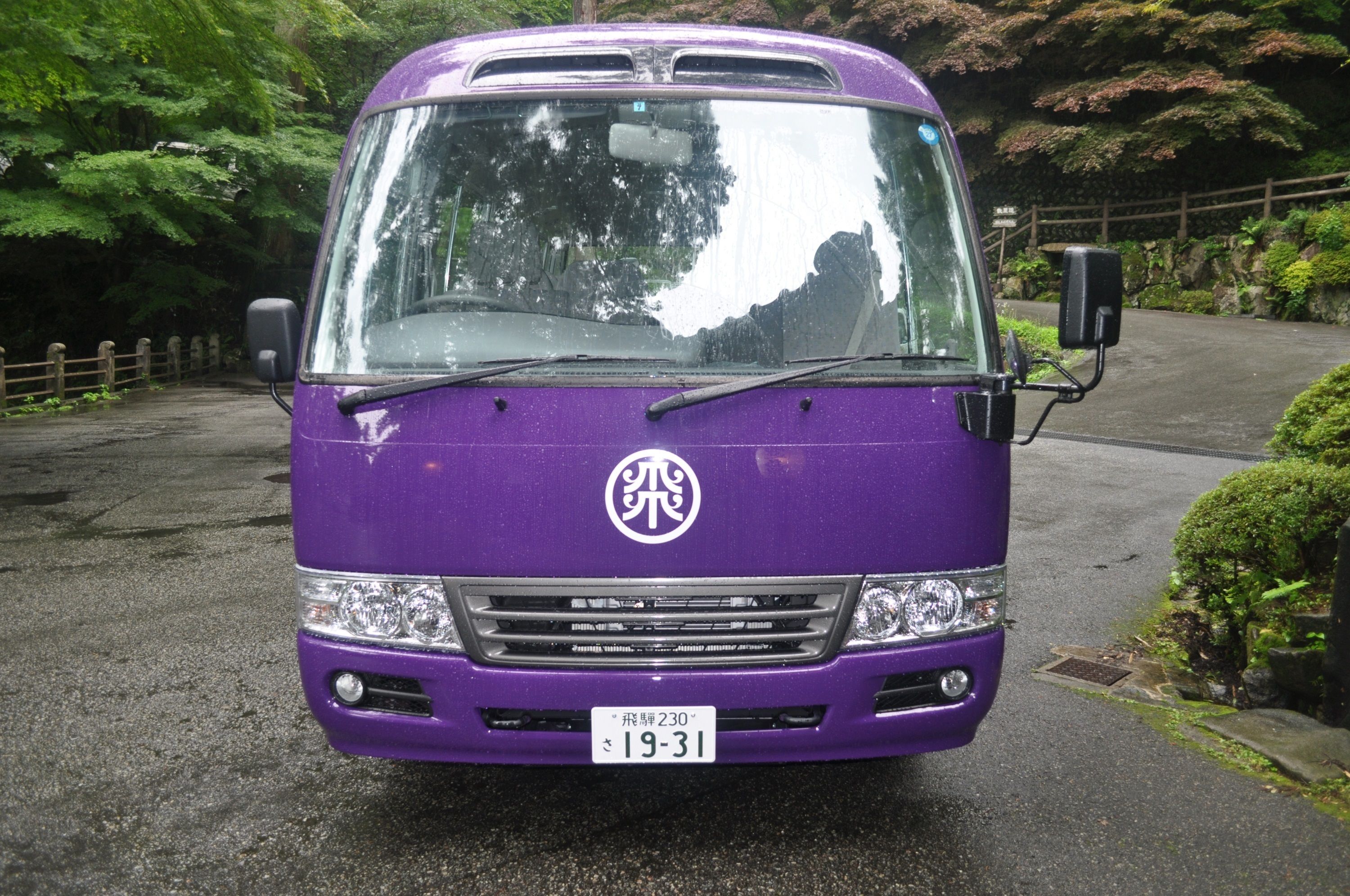 A purple bus with a visible license plate and a logo on the front.