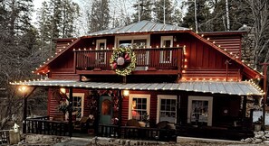 A log cabin with a balcony, decorated with lights and a wreath.