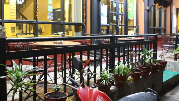 An outdoor seating area with tables and chairs, potted plants, and a railing. - Hotel Buddha Land (Kathmandu)
