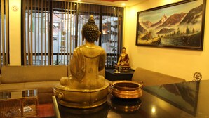 A room with a Buddha statue, a painting of mountains, and a sofa. - Hotel Buddha Land (Kathmandu)