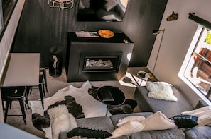 A modern living room with a fireplace, a sofa, a coffee table, and a television. - The Lofts Apartments (Queenstown)