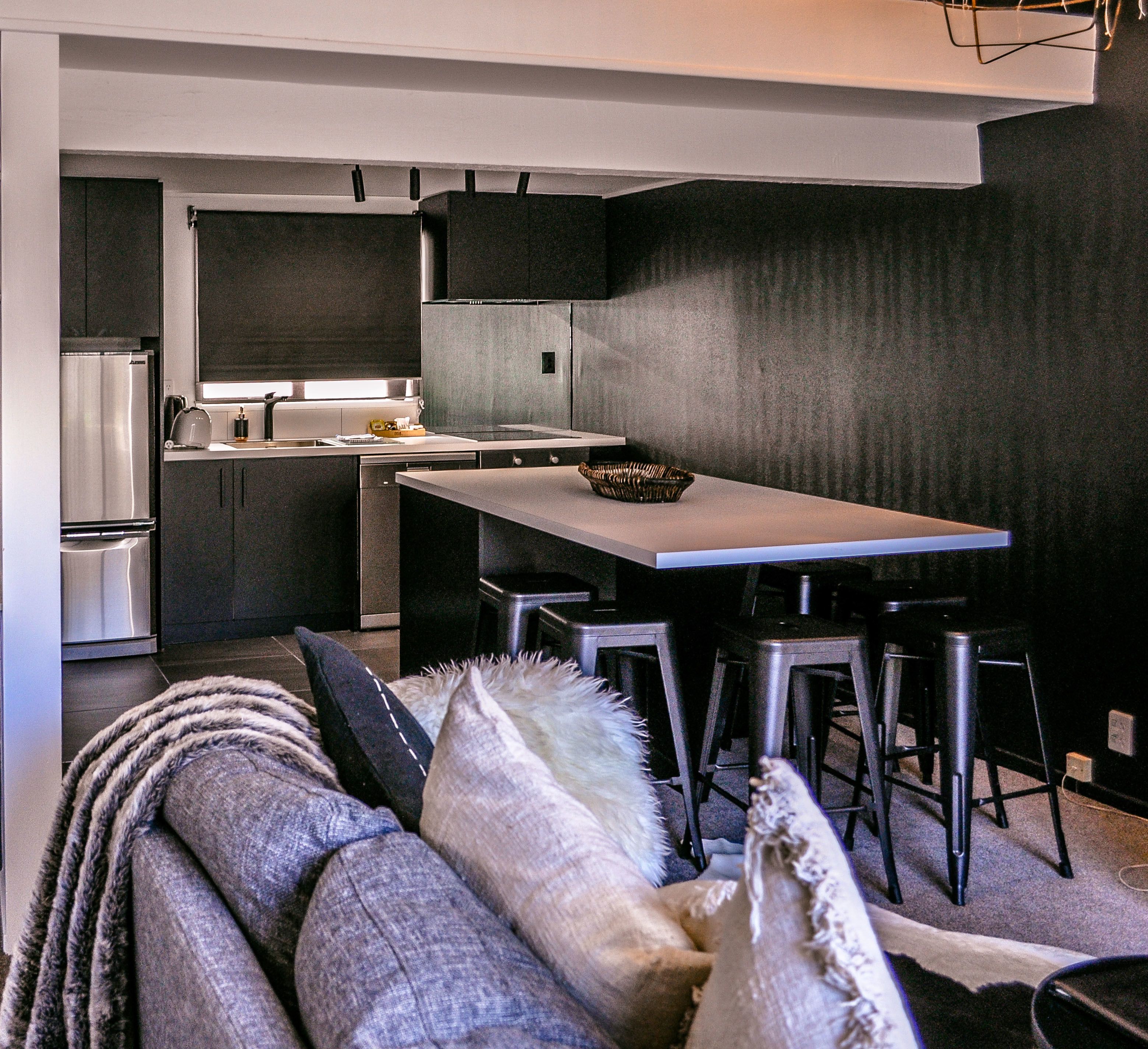 Una cocina moderna con comedor, que incluye un refrigerador, estufa y muebles oscuros.