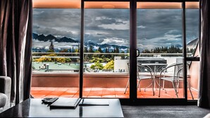 Une pièce dotée d’une grande fenêtre donnant sur un balcon aménagé avec des chaises et une table.