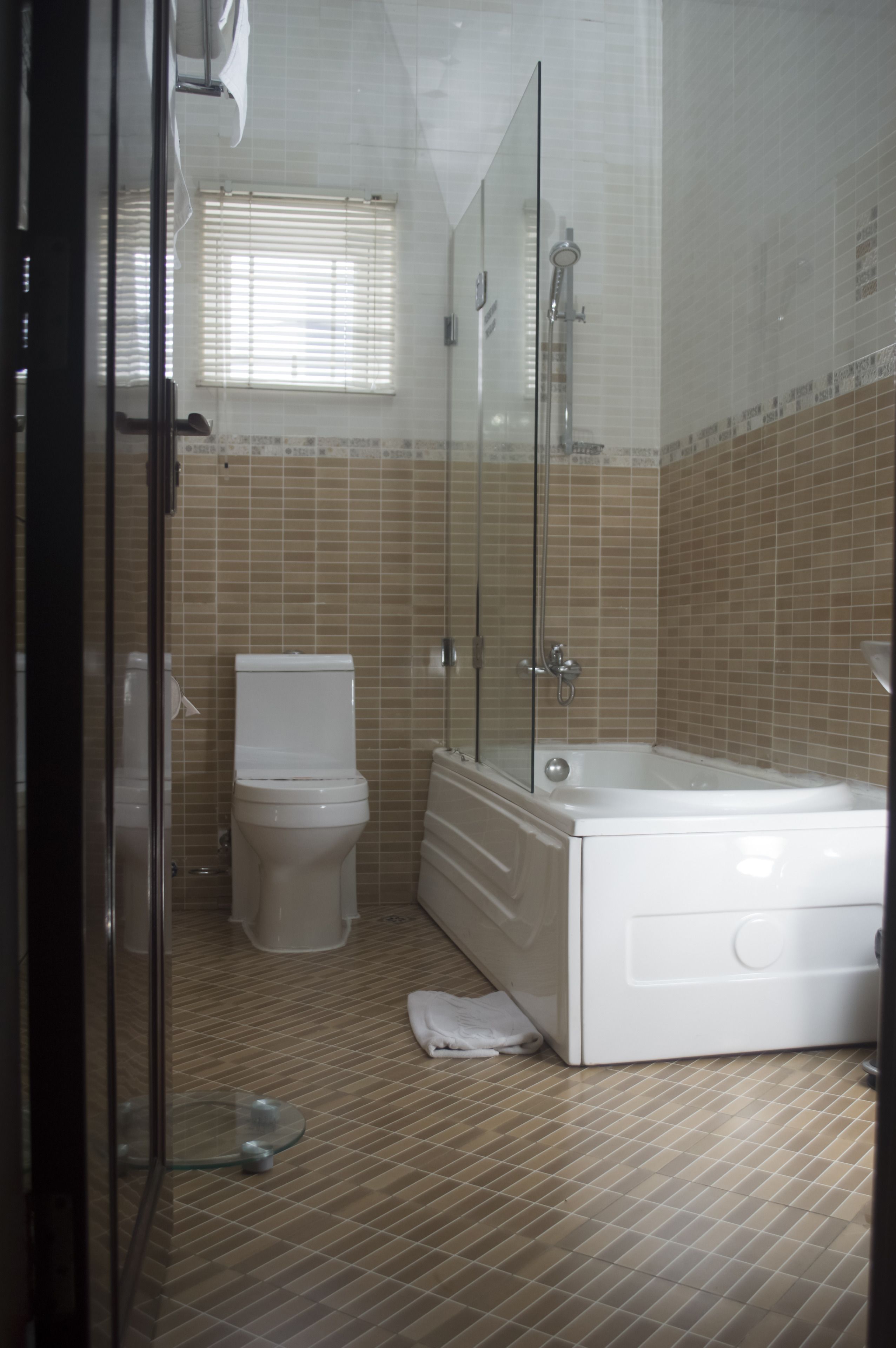 A bathroom with a toilet, a bathtub, and a glass shower enclosure.