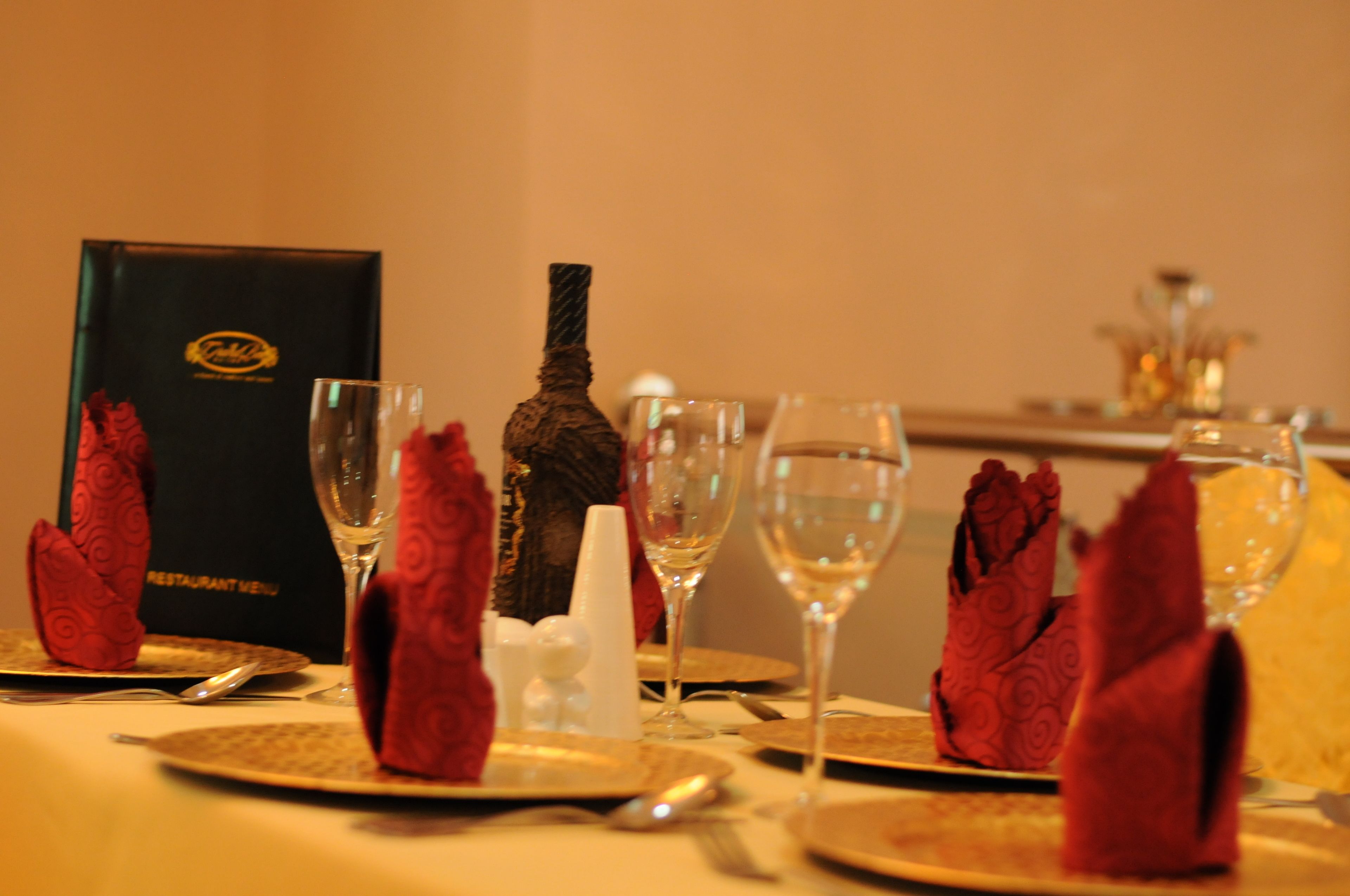 A table set with red napkins, wine glasses, and a menu box.
