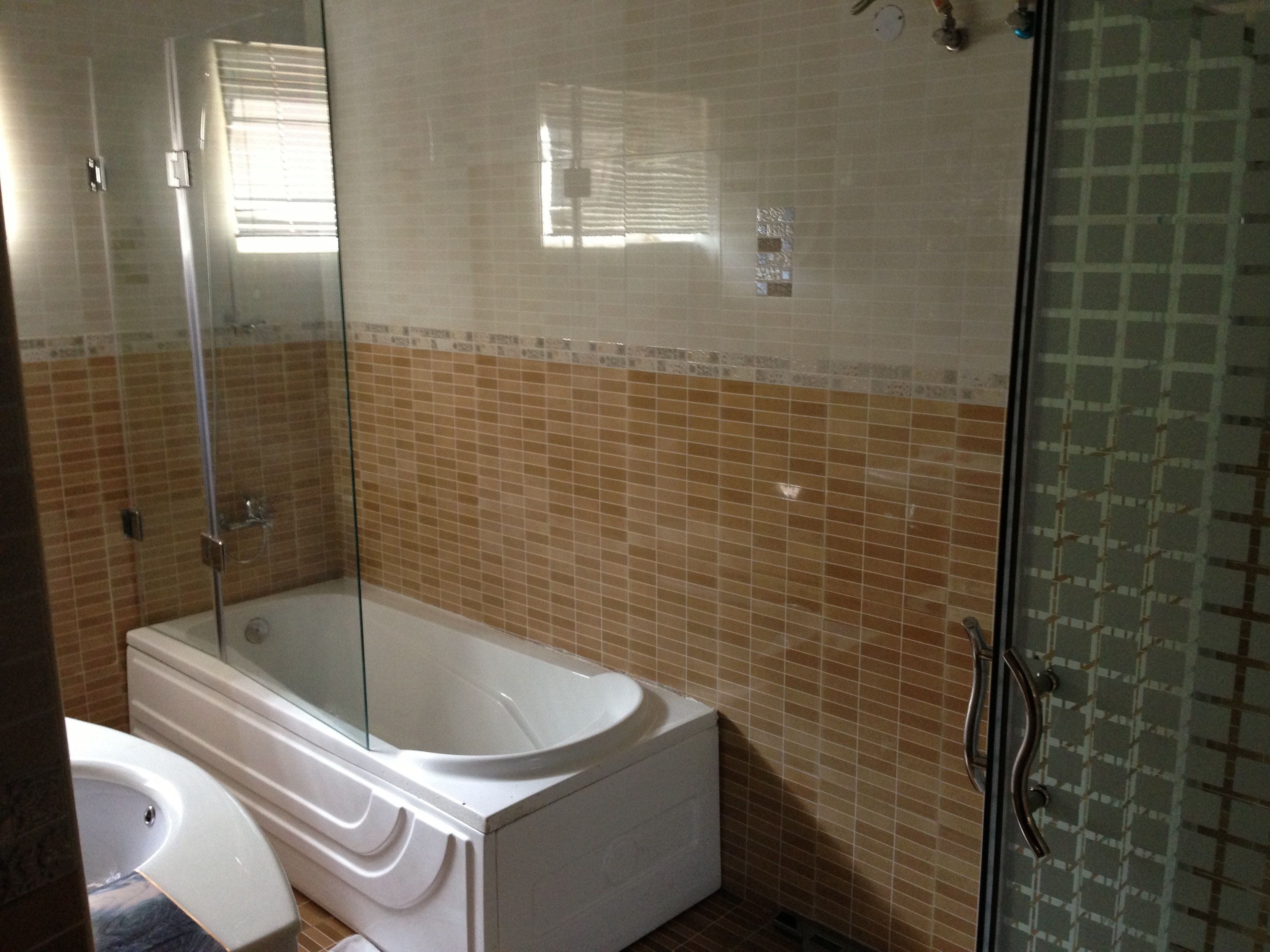 Une salle de bain avec une baignoire, une cabine de douche en verre et des murs carrelés.