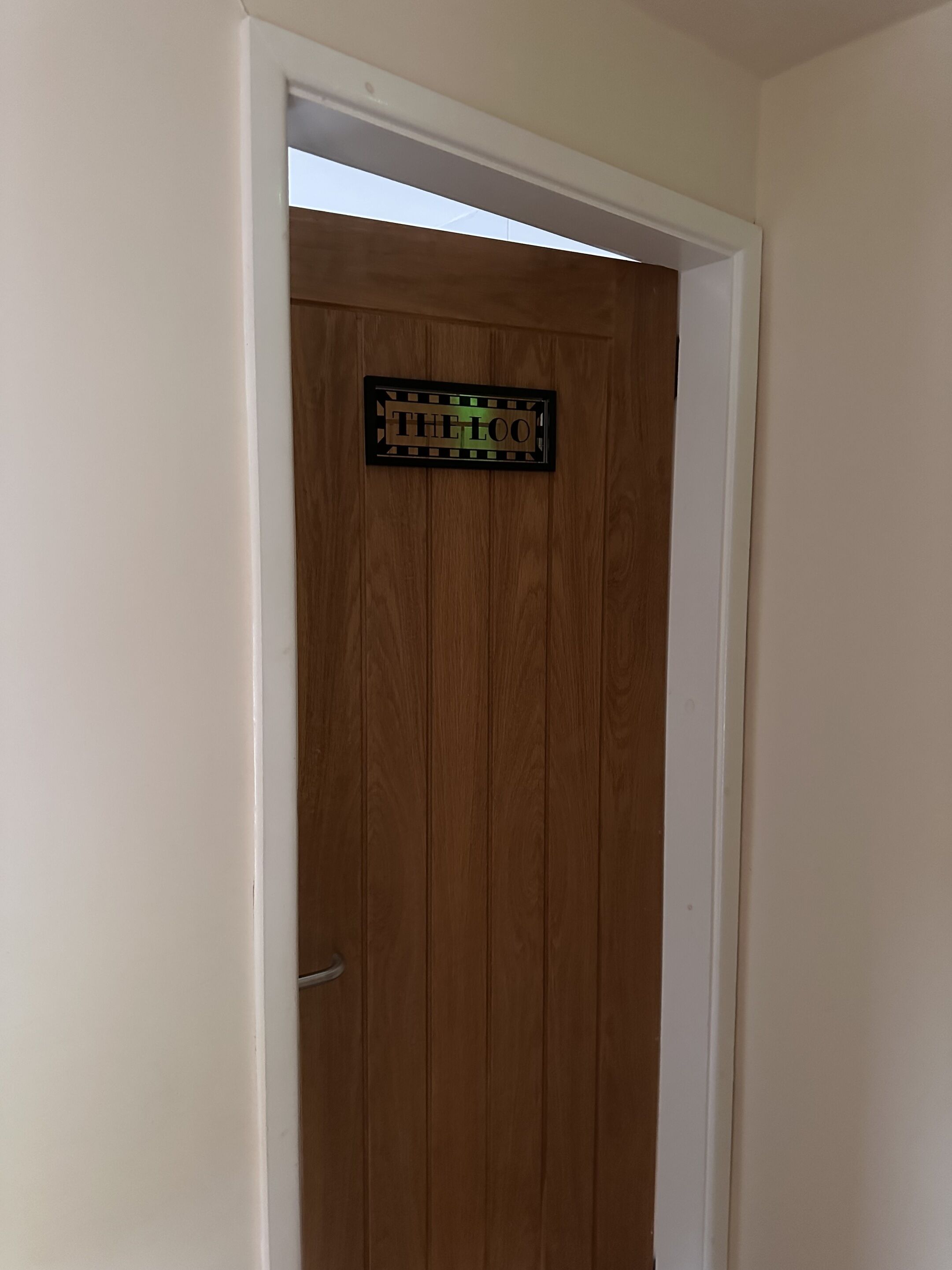 A wooden door with a sign that reads "THE LOO".
