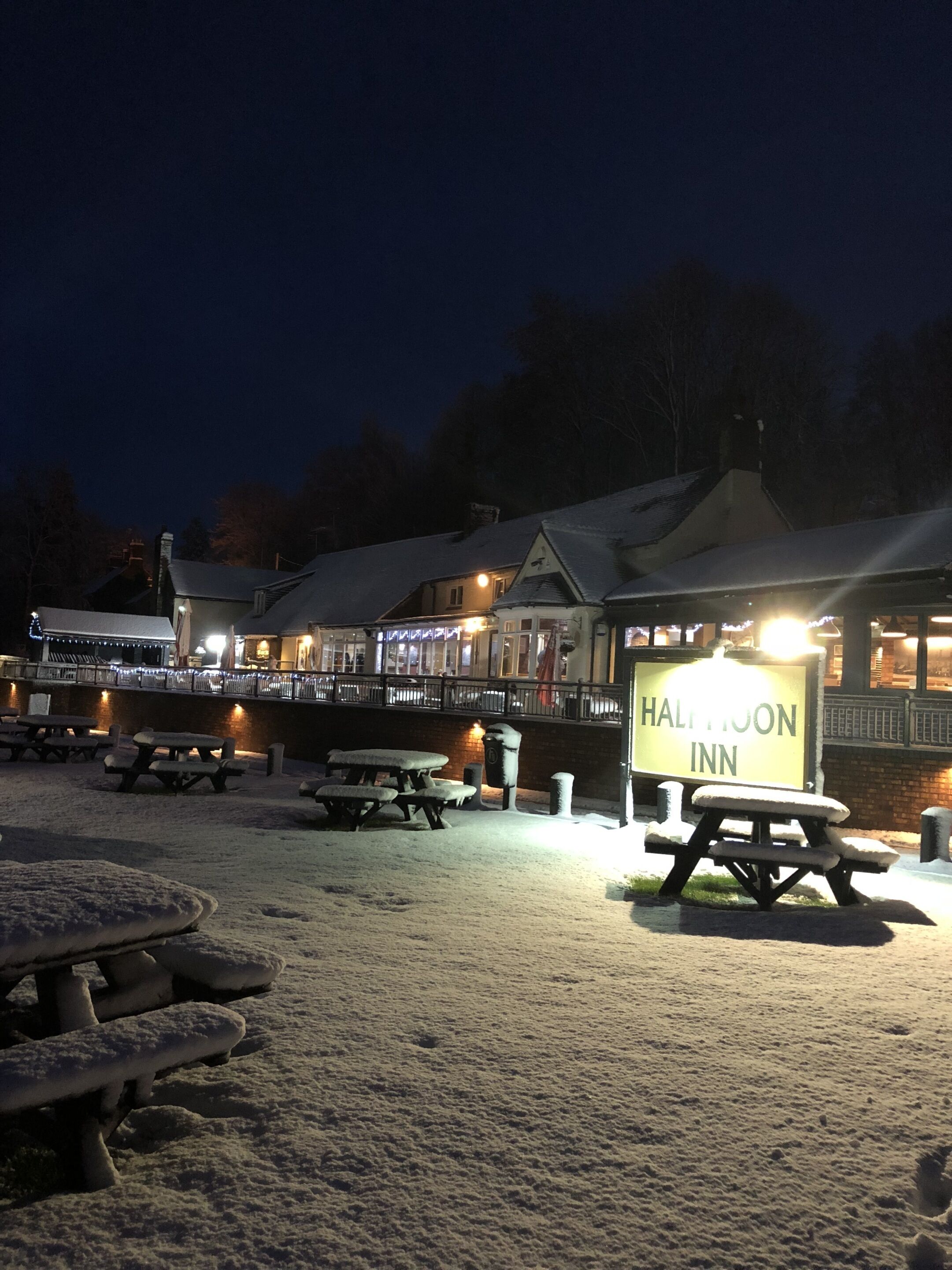 A snow-covered outdoor area with picnic tables and a sign for the Halton Inn.