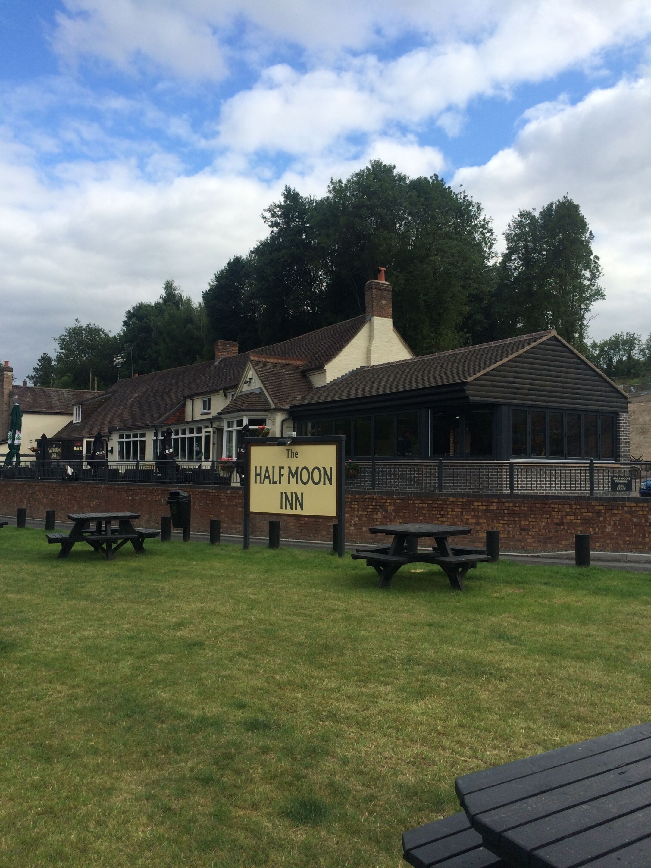 The Half Moon Inn with a signboard, outdoor seating, and a brick facade.