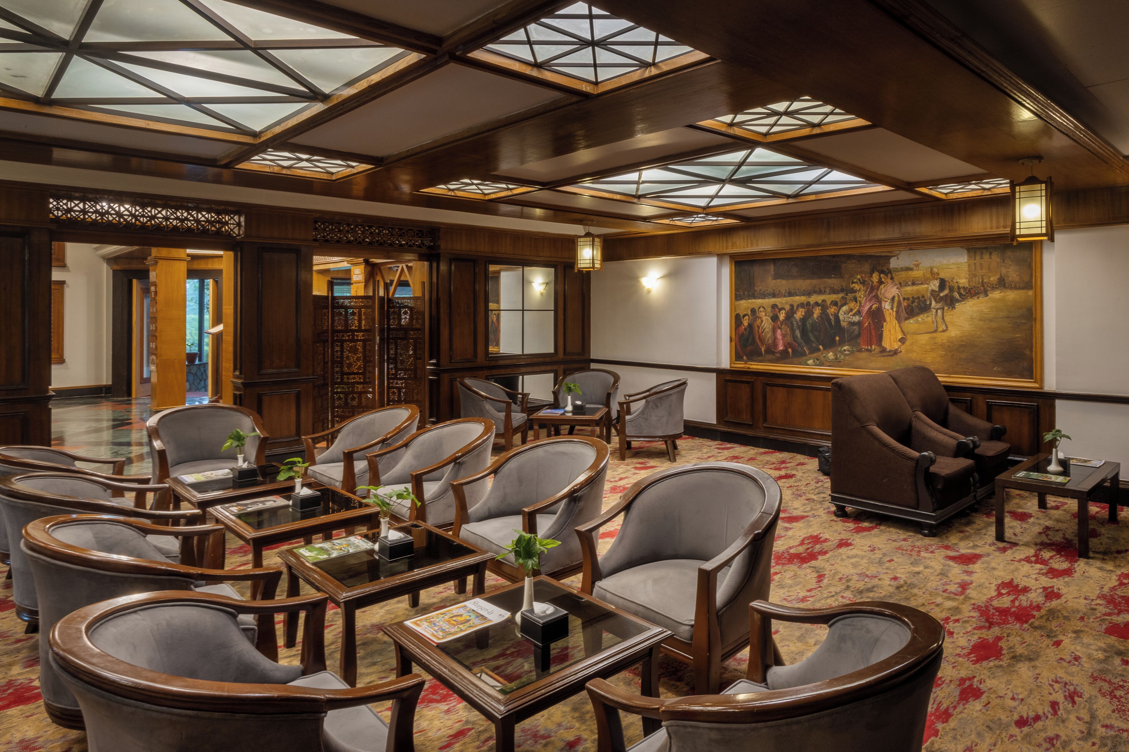 A hotel lobby with a high ceiling, geometric skylights, and a large mural.