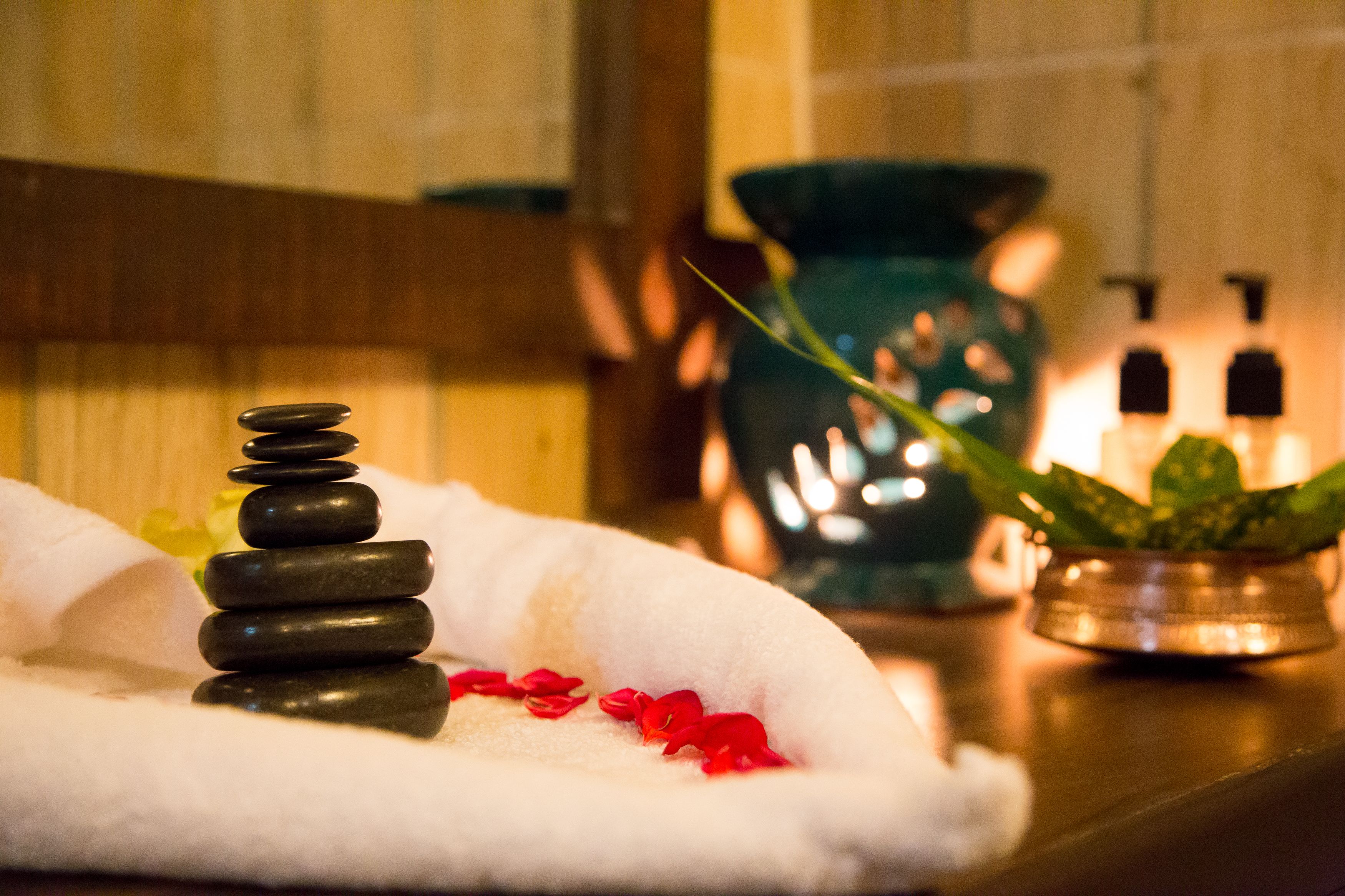 Un entorno de spa con una toalla, una pila de piedras y una planta en maceta.