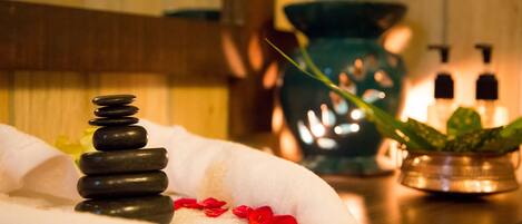 A spa setting with a towel, a stack of stones, and a potted plant.