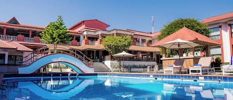 Een buitenzwembad, parasols voor strand/zwembad