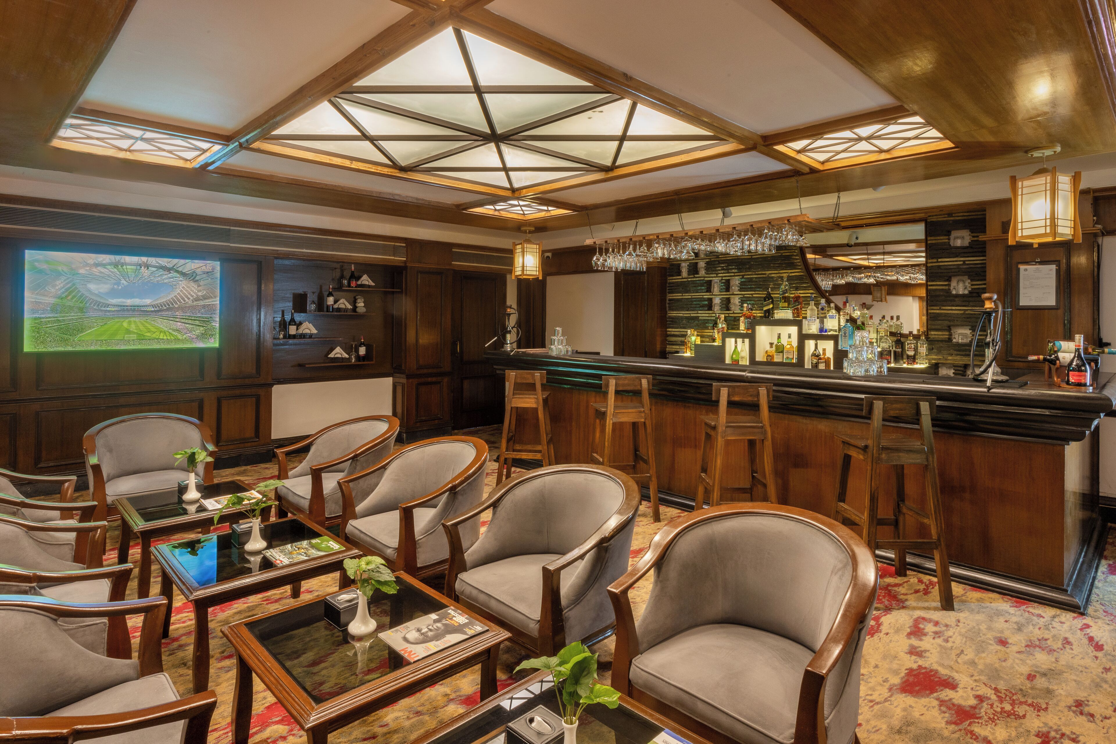 Zona de bar con mobiliario de madera y un techo alto con tragaluces.