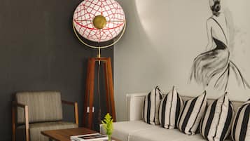 Un salon moderne avec un canapé, une table basse en bois, un lampadaire et un tableau accroché au mur.