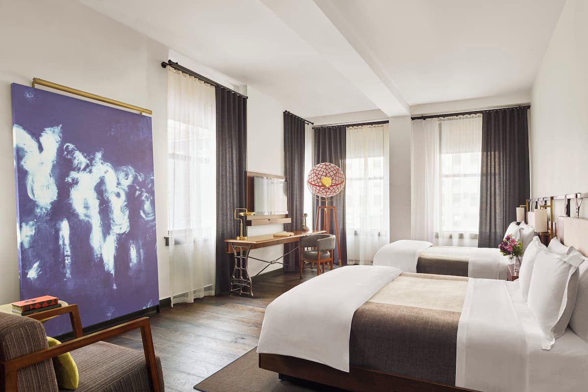 Ein Hotelzimmer mit einem großen Bett, einem Schreibtisch mit Stuhl, einem Fernseher und einem Bild an der Wand.