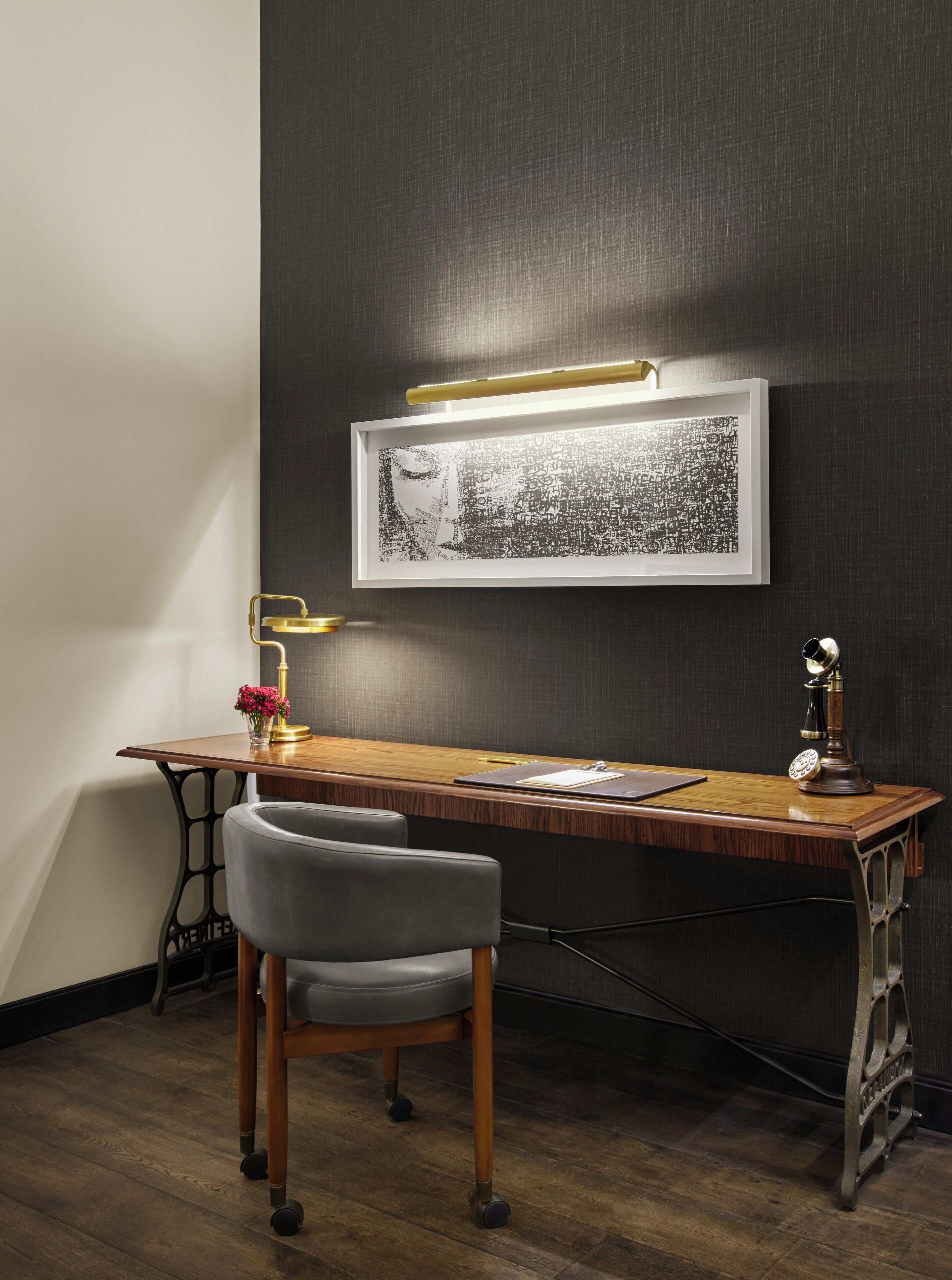 A modern office desk with a framed artwork, a vintage telephone, and a desk lamp.