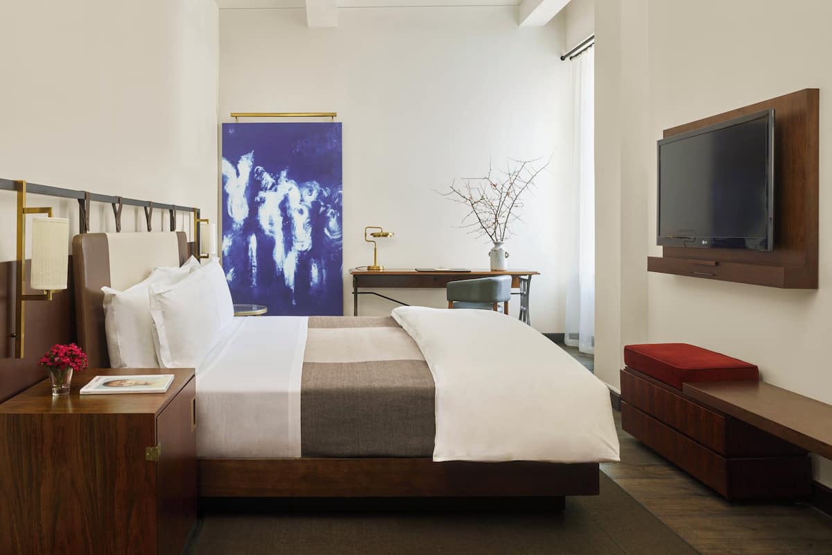 Ein modernes Hotelzimmer mit einem großen Bett, einem Schreibtisch, einem Fernseher und einem Bild an der Wand.