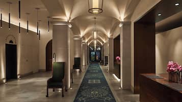 Un hall d’hôtel avec un long couloir, un comptoir d’accueil et une chaise.