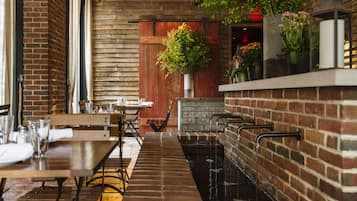 Un restaurante con paredes de ladrillo, mesas de madera y una larga barra con fuente de agua.
