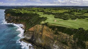 A coastal golf course with a cliff overlooking the ocean.