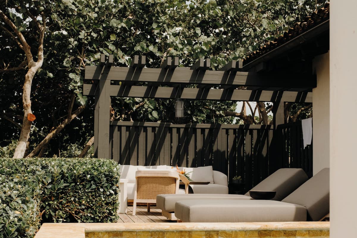A pool area with a seating arrangement and a pergola.