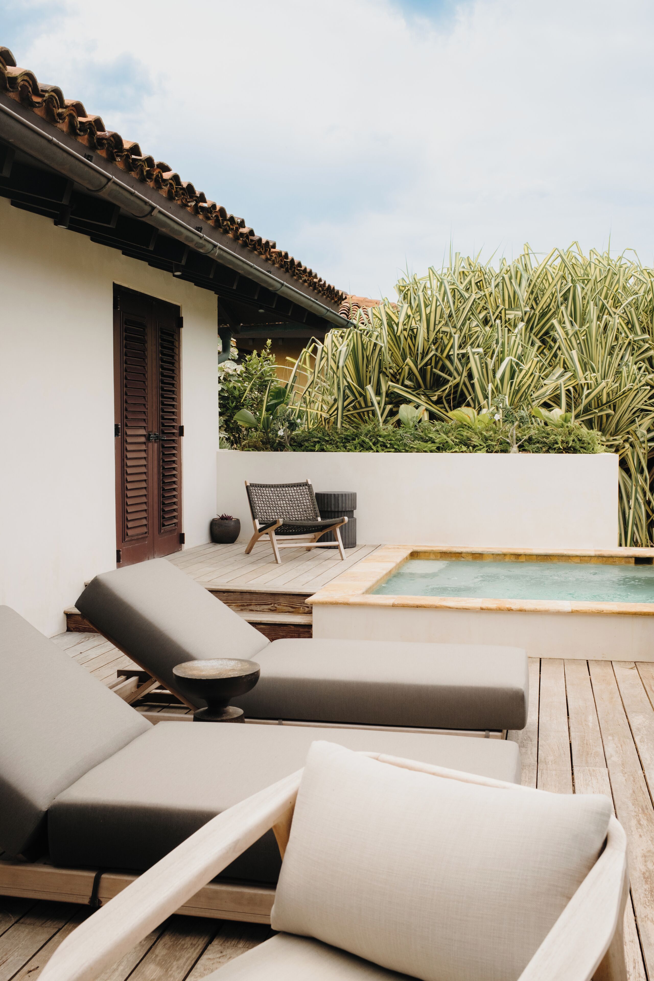 Un espace aménagé au bord de la piscine, avec des chaises longues, une petite table et une porte.